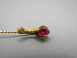 a close up of a red stone on a gold stick