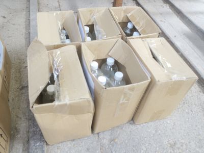 six bouteilles d'eau dans un carton posé sur le trottoir