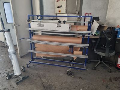 Plusieurs rouleaux de papier sont empilés sur un rayonnage dans une pièce