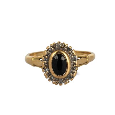 gros plan d'une bague en or avec une pierre noire