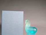 une sculpture en verre bleu représentant un oiseau, à côté d'une boîte bleue