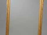 un miroir orné d'un cadre doré sur fond gris