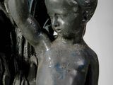 a statue of a boy holding a birdbath on top of a fountain