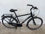 un vélo noir garé dans un garage, près d'un mur