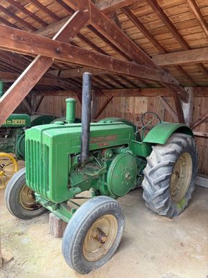 un tracteur vert garé à l'intérieur d'une grange au toit en bois