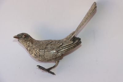 un oiseau argenté posé sur une surface blanche
