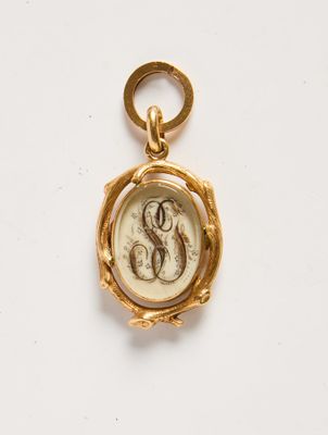 un gros plan d'une breloque en or portant un monogramme