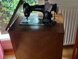 a sewing machine sitting on a wooden table in front of a window
