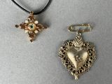 deux bijoux posés sur une table, avec une croix et un cœur
