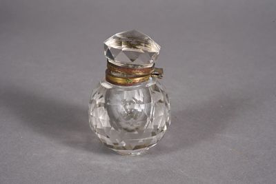 an antique glass perfume bottle with a gold lid on a gray surface