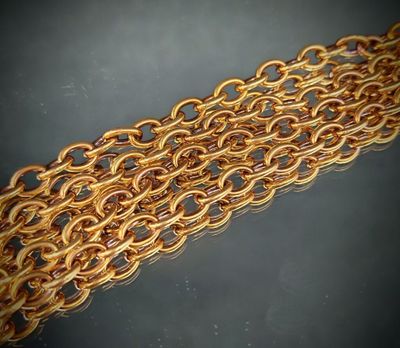 gros plan d'un bracelet en chaîne en or sur une surface noire