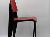 a black chair with a red seat on a white background