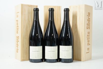 trois bouteilles de vin rouge dans un coffret en bois posé sur une surface blanche