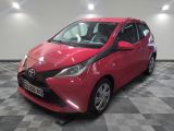 une Toyota AY rouge garée dans une pièce au sol à carreaux