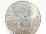 an image of a coin on a white surface with a building in the background