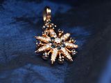 an image of a gold and diamond pendant on a blue cloth