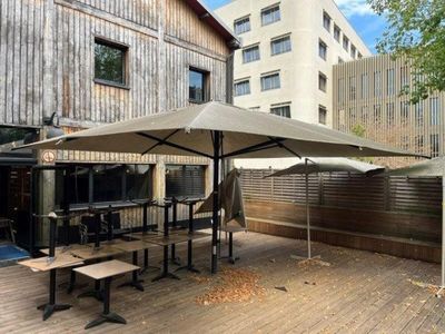 tables and umbrellas on the wooden deck outside of a building
