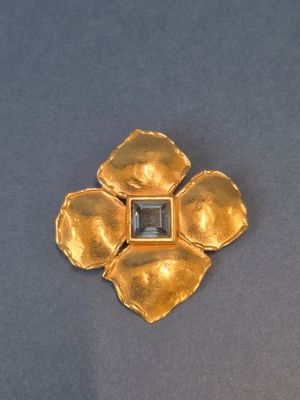 une broche en forme de fleur en or, ornée d'une pierre noire au centre
