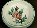 a small plate with a rose on it next to a smaller plate with a flower on it