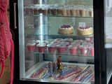 une femme debout devant une vitrine remplie de gâteaux