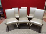 six chaises de salle à manger en cuir crème dans une pièce dont l'un des murs est rouge