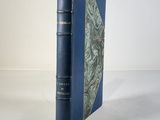 an old book with a blue cover sitting on top of a white table