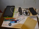a picture of a table with a cell phone, a pen, a cell phone, a notepad, a cell phone, and other items