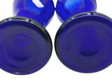 two blue glass plugs with black caps on a white background
