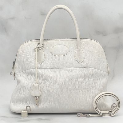 white leather handbag with strap and wrist strap on white background