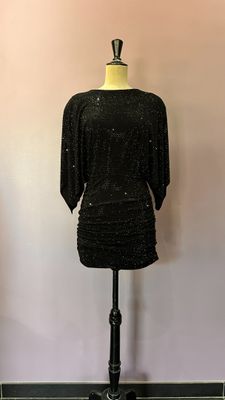 une robe noire posée sur un mannequin devant un mur