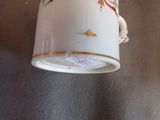 a white cup with a gold trim and a bird on it