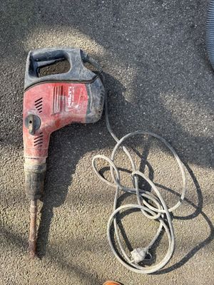 a cord and a drill on the ground next to a pair of shoes