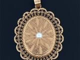 une image représentant un pendentif en or orné d'une perle au centre
