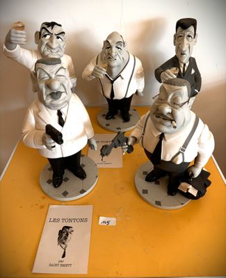 trois figurines représentant des hommes en costume-cravate posées sur une table jaune