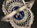 a close up of a brooch with a blue stone in it