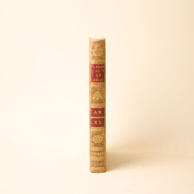 un vieux livre posé sur une table à côté d'un mur blanc