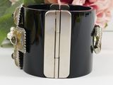 black and silver cuff bracelet with two metal bars and a flower