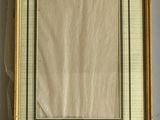 an old picture frame hanging on a wall with a ribbon around it