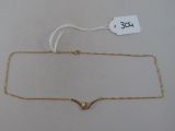 gros plan d'un collier en or sur une surface blanche
