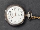 a silver pocket watch with a chain on a black surface