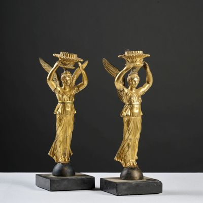 une paire de figurines en bronze doré représentant des femmes portant des paniers sur la tête