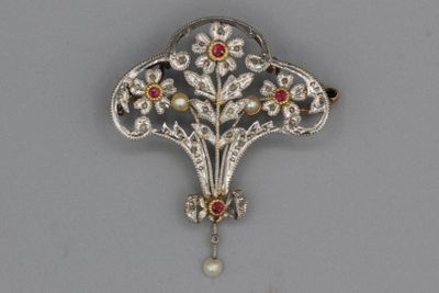 un gros plan d'une broche ornée d'une perle et d'une fleur