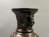 un vase en bronze orné d'un motif représentant un cheval et son cavalier