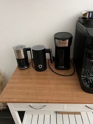 a small table with a coffee maker and cups on it