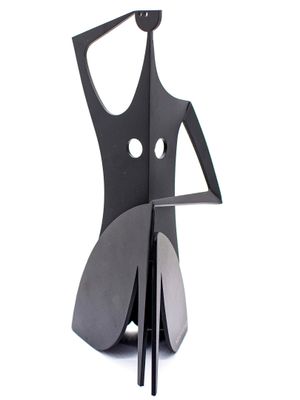 a metal sculpture of a woman sitting on top of a chair