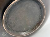 a black vase with a brown rim sitting on a white surface