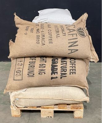 trois sacs de café sont posés sur une palette devant un mur noir