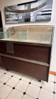 un comptoir en verre au milieu d'une pièce, avec un tableau accroché au mur derrière lui