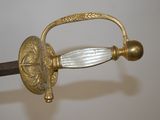 a gold sword with a glass handle on a white wall