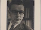 portrait of a man wearing glasses and a suit in a library